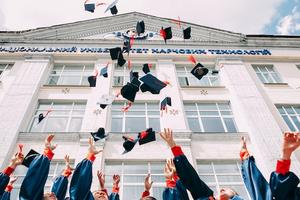 Universitarios acabados de graduar lanzando sombreros al aire