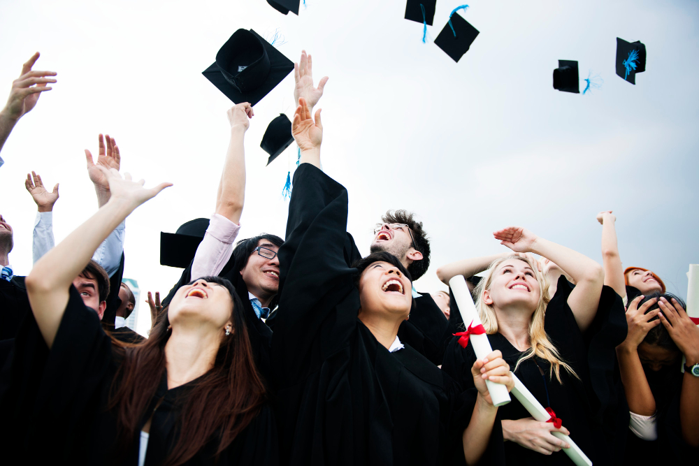 Estudiantes lanzando los sombreros de reciengraduados hacia arriba