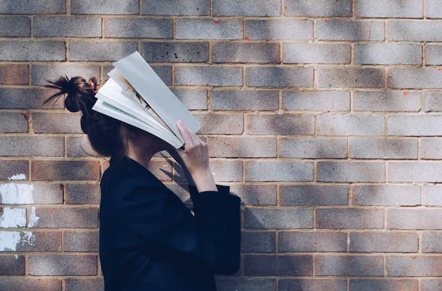 Estudiante cubriéndose el rostro con un libro